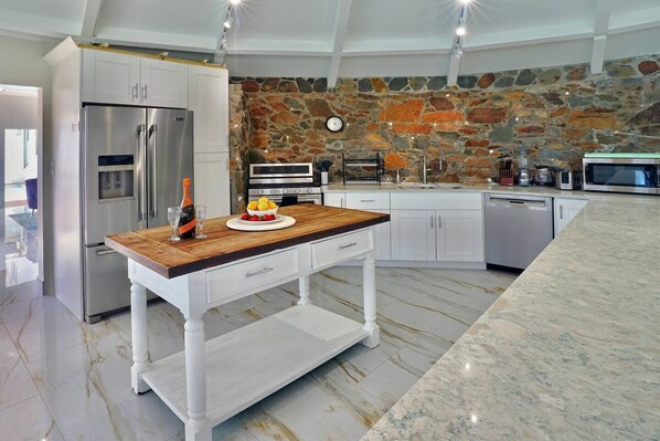 A modern kitchen with a stone wall, stainless steel appliances, and a wooden island.