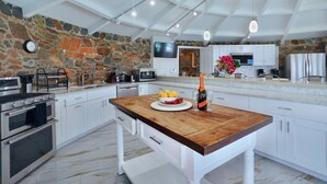 Una cocina moderna con armarios blancos, una pared de acento de piedra y una isla de madera.