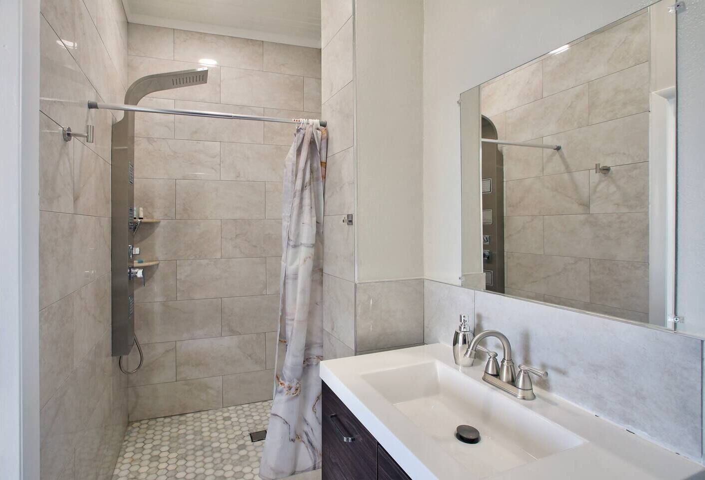 Une salle de bain moderne avec une douche, un lavabo et un miroir.