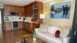 A modern kitchen with wooden cabinets, stainless steel appliances, and a dining area with a white sofa and a coffee table. - Beachfront, Corner Unit Sapphire, Restaurants, Pool (St. Thomas)