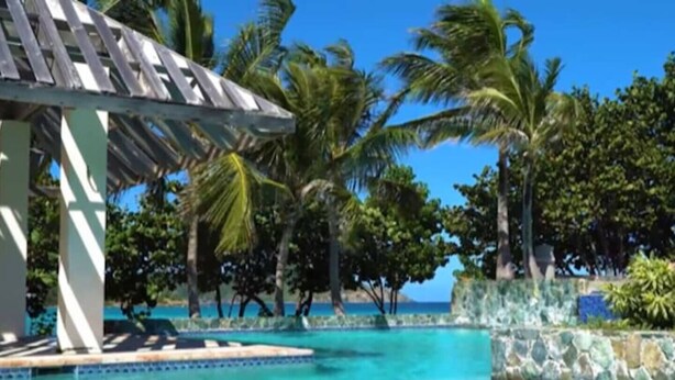 A pool area with a wooden pergola, palm trees, and a view of the ocean. - Beachfront, Corner Unit Sapphire, Restaurants, Pool (St. Thomas)