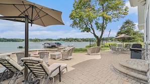 Une terrasse extérieure avec des chaises longues, un barbecue et une vue sur le lac.