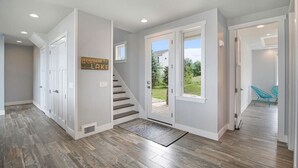 Un hall d’entrée spacieux avec un plancher en bois, un escalier menant à un jardin arrière et une pancarte de bienvenue.