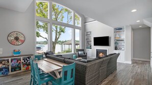 Un salon moderne doté d’une cheminée, d’une grande fenêtre donnant sur un lac et d’un téléviseur fixé au mur.