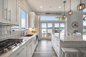 A modern kitchen with a large island, white cabinetry, and a view to the outside.