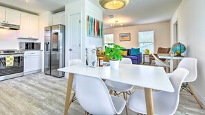 A modern kitchen with white cabinets, stainless steel appliances, and a dining area with white chairs and a table. - Near Downtown + Ocean: Sarasota Getaway (Sarasota)