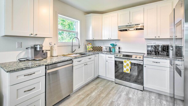 A modern kitchen with white cabinets, stainless steel appliances, and a granite countertop. - Near Downtown + Ocean: Sarasota Getaway (Sarasota)