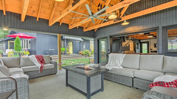 A cozy outdoor seating area with wicker furniture, a central fire feature, and a view of the garden.