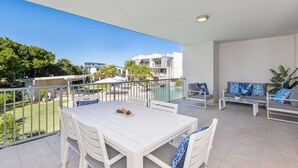 Un balcone con tavolo e sedie bianche, un divano e vista sulla zona circostante.