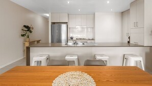 Una cucina moderna con isola centrale, mobili bianchi e frigorifero in acciaio inossidabile.