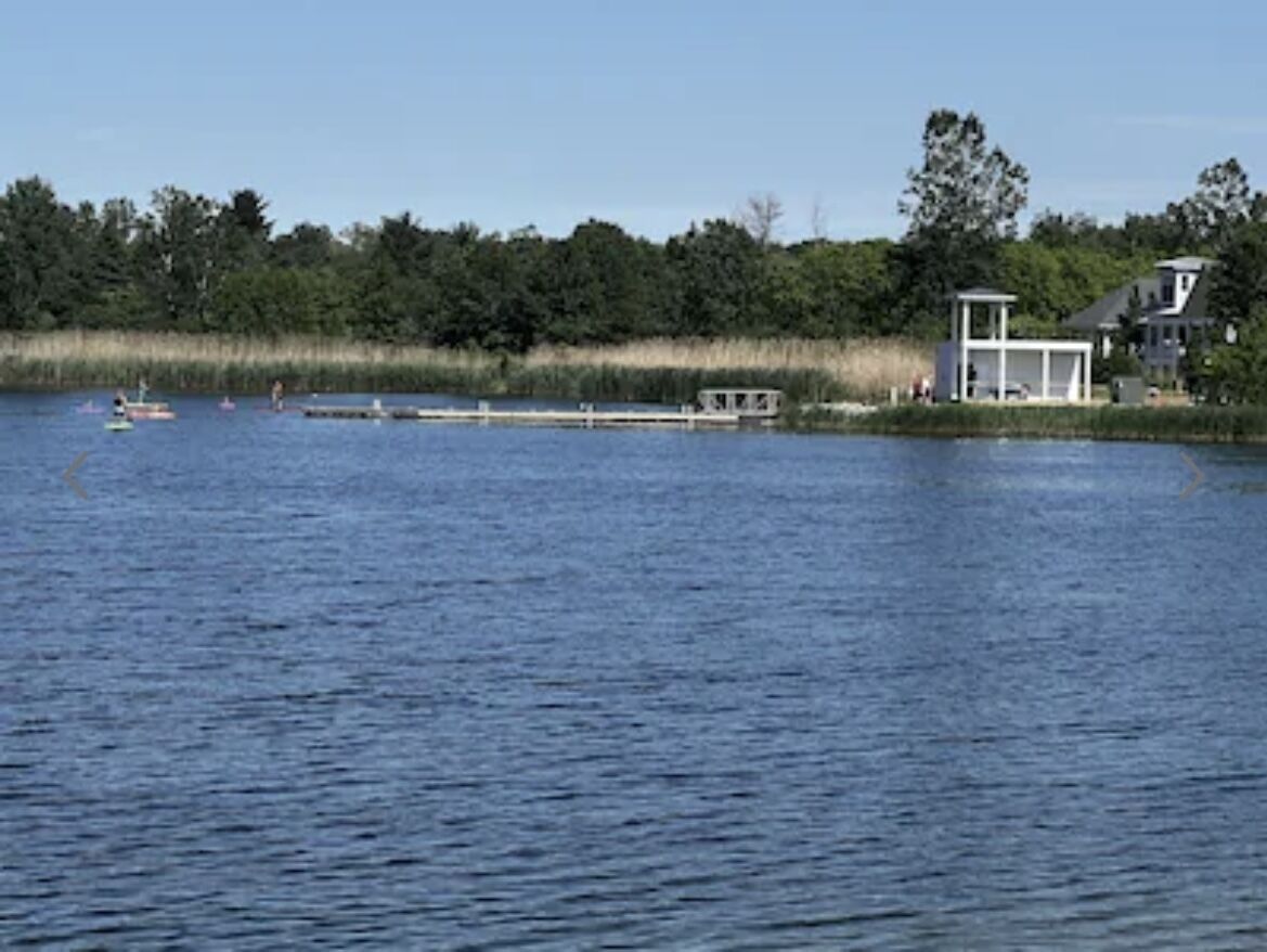 Uitzicht op een meer met een steiger, een klein bootje en een huis met een overdekte veranda.