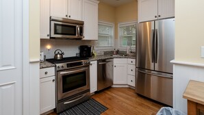 Cocina compacta con armarios blancos, electrodomésticos de acero inoxidable y encimera de granito.