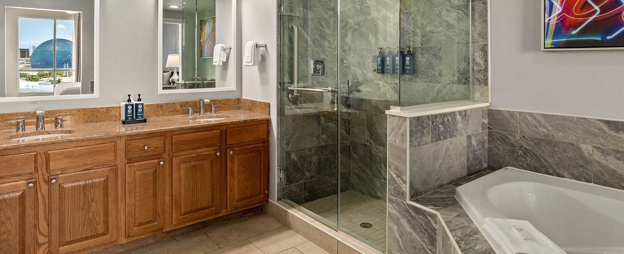 A modern bathroom with a glass-enclosed shower, a bathtub, and wooden cabinetry.