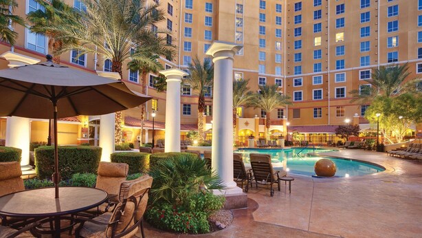 A hotel courtyard with a swimming pool, outdoor seating, and palm trees. - 2 Bed 2 Bath Las Vegas - Pools, Hot Tubs, Cabanas and More! (Las Vegas)