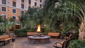 A courtyard with a stone fire pit, benches, and lush greenery. - 2 Bed 2 Bath Las Vegas - Pools, Hot Tubs, Cabanas and More! (Las Vegas)