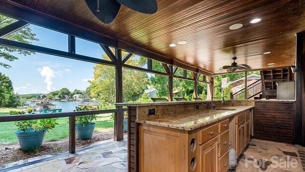 A spacious kitchen with a large island, stone flooring, and a view of a backyard with a pool. - Lakefront home with private beach & gourmet kitchen (Sherrills Ford)