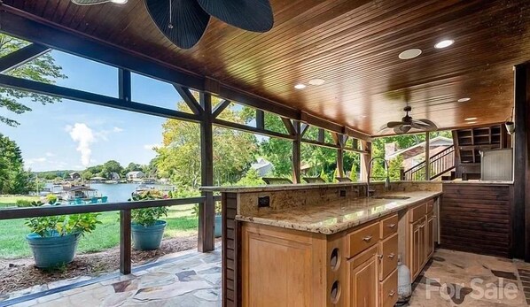 Una cocina amplia con una isla grande, piso de piedra y vista a un patio trasero con piscina.