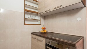 Una cuina amb forn integrat, taulell de fusta i una cistella penjada a la paret.