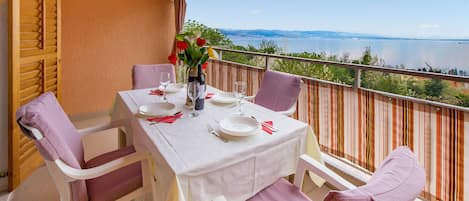 Una mesa en un balcón dispuesta para dos personas, con vistas a un lago y montañas.