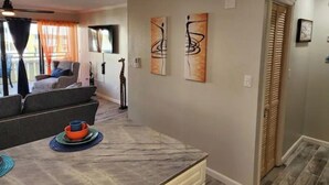Ein modernes Wohnzimmer mit einer Couch, einem Esstisch mit Tellern und abstrakter Kunst an den Wänden.