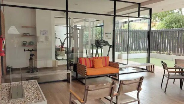 Una sala de estar moderna con un separador de vidrio, un sofá y un comedor con sillas.