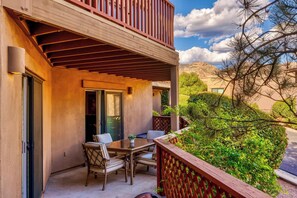A balcony with a table and chairs, a wooden railing, and a view of a mountain.