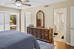 Un dormitorio con cama, cómoda y ventilador de techo.