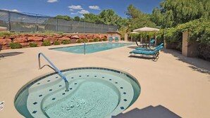 Ein Swimmingpool mit Whirlpool, Liegestühlen und einer überdachten Sitzgelegenheit.
