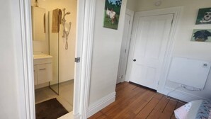 A bathroom with a glass shower enclosure, a white sink, and a wooden floor. - Warm and welcoming, private one bedroom on a lifestyle property. (Waingawa)