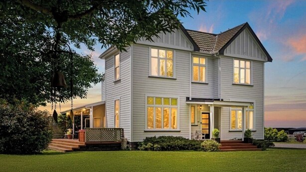 A two-story house with a front porch, a visible staircase, and a well-maintained lawn. - Warm and welcoming, private one bedroom on a lifestyle property. (Waingawa)