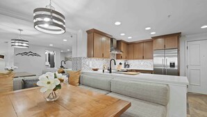 A modern kitchen with wooden cabinets, a built-in oven, and a stainless steel refrigerator.