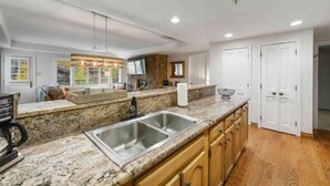 A modern kitchen with granite countertops, a double sink, wooden cabinets, and a stone backsplash. - Lodge Tower 487 3BR at the base of Vail Mountain (Vail)