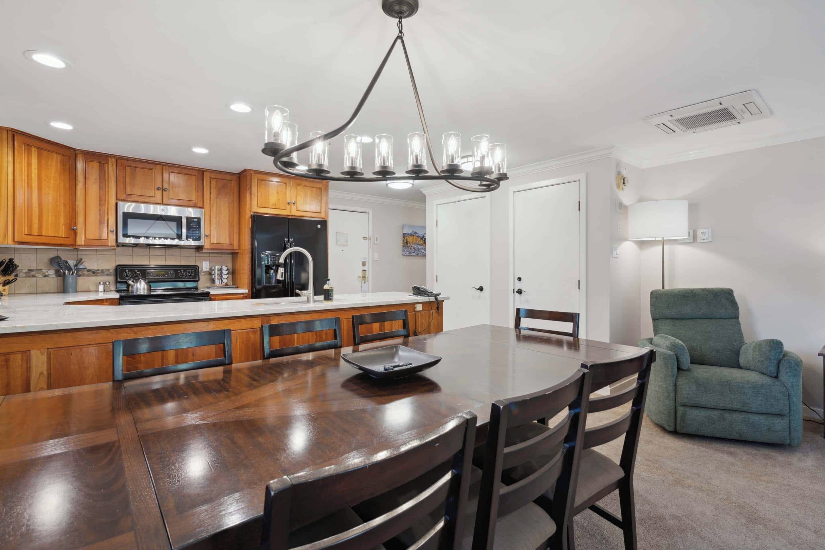 A modern kitchen with wooden cabinets, a stainless steel refrigerator, and a large island with seating.