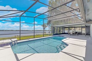 A swimming pool with a view of a lake, surrounded by a covered patio area with seating. - ☆LakeHouse 4 Bedroom Newly Renovated Heated pool ☆ (Orlando)
