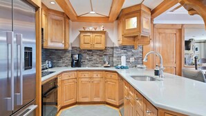 Une cuisine moderne avec des meubles en bois, un réfrigérateur en acier inoxydable et un plan de travail en granit.