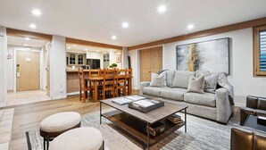 A modern living room with a sofa, ottoman, coffee table, and a dining area with chairs and a table. - Lodge Tower 287 3BR at the base of Vail Mountain (Vail)