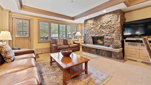 A living room with a stone fireplace, leather sofa, and a flat-screen TV.