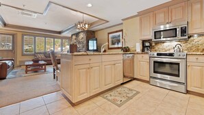 A spacious kitchen with wooden cabinets, a built-in oven, and a microwave. There is a stone accent wall and a large window providing natural light.