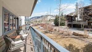 A balcony with wicker furniture and a view of a snowy mountain landscape.