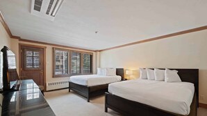 A hotel room with two beds, a desk, and a TV.
