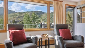 Un balcon avec deux fauteuils gris, une petite table et une vue sur un paysage montagneux.