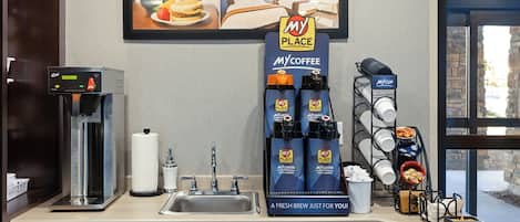 A hotel kitchenette with a coffee machine, My Coffee dispensers, and a My Place sign advertising breakfast in bed.