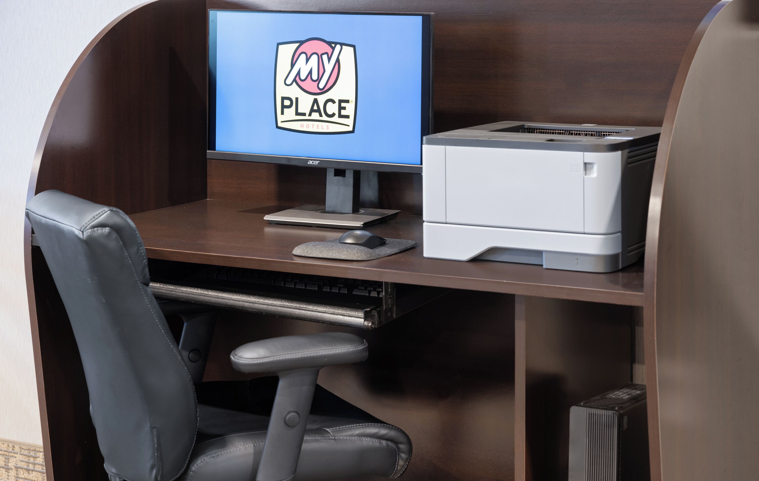 A computer desk with a monitor, printer, and office chair.
