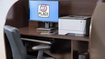 Escritorio con monitor, impresora y silla de oficina.