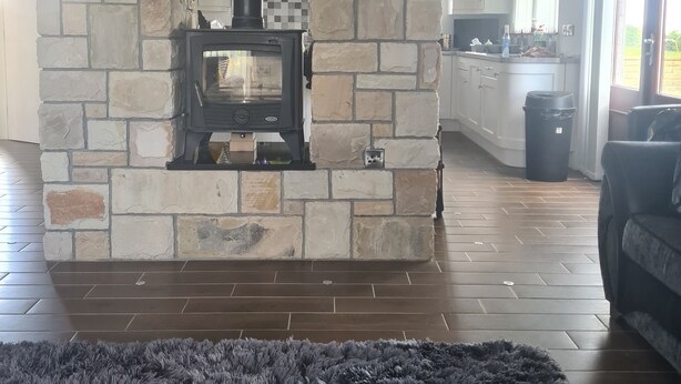 A living room with a stone fireplace, a framed photograph above it, and a dark rug on the floor.