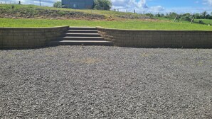 A gravel driveway leading to a building with a metal roof and brick walls.