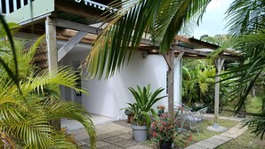 A covered outdoor area with a wooden pergola, potted plants, and a seating area. - Le petit coin de campagne  (Le Robert)