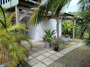 Un espace extĂ©rieur abritĂ©, dotĂ© dâune pergola en bois, de plantes en pot et dâun coin salon.