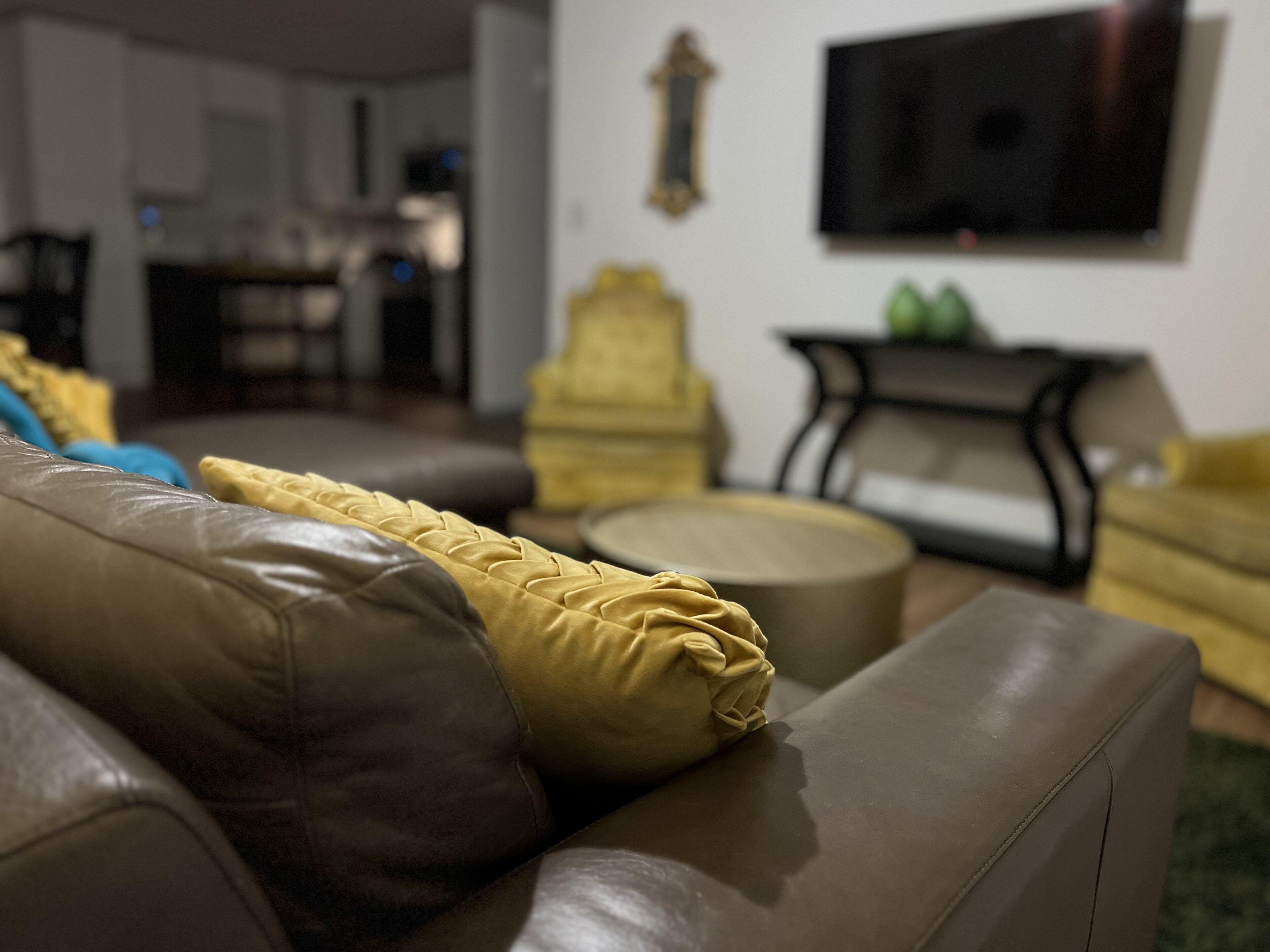 A living room with a brown leather sofa, a yellow armchair, and a round coffee table.