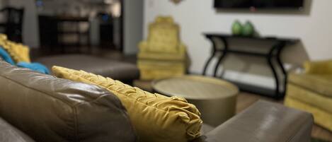 A living room with a brown leather sofa, a yellow armchair, and a round coffee table.